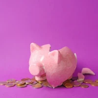 cofrinho rosa quebrado com moedas espalhadas em fundo roxo representando fundo de funil de marketing