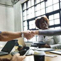 Pessoas em reunião de negócios em um escritório apertando as mãos, representando artigo sobre empresas B2B da Orgânica.