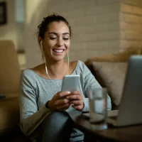 mulher-sorrindo-fones-ouvido-smartphone-sofa.jpg