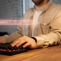 Pessoa usando teclado de computador com uma busca online, representando a importância da autoridade tópica no SEO na era da inteligência artificial.