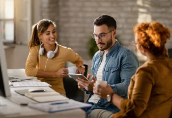 Tr&ecirc;s jovens profissionais em reuni&atilde;o de trabalho colaborativa em escrit&oacute;rio, ilustrando um conte&uacute;do da Org&acirc;nica sobre marketing cont&iacute;nuo.