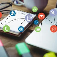Mesa de trabalho com notebook, caderno e ícones de comunicação digital, representando o inbound marketing.