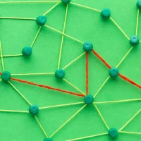 Rede de conexões com alfinetes verdes e fios amarelos e vermelhos em fundo verde representando rede de comunicação