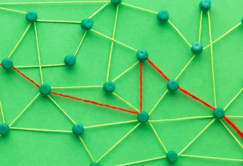 Rede de conexões com alfinetes verdes e fios amarelos e vermelhos em fundo verde representando rede de comunicação