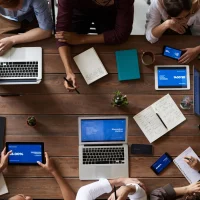 Equipe de trabalho reunida em mesa com laptops, tablets, smartphones, cadernos e café, que ilustram um artigo da Orgânica sobre tipos de conteúdo.